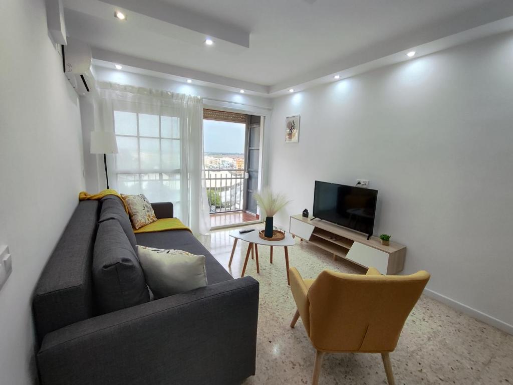 sala de estar con sofá y TV en Precioso apartamento en Sevilla., en Camas