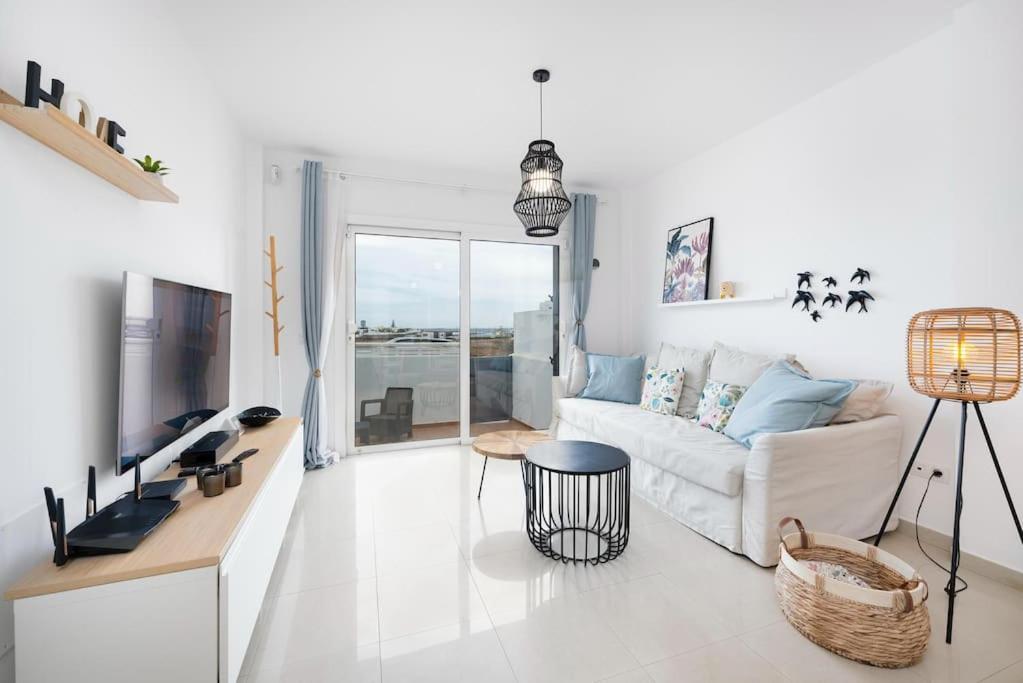 ein weißes Wohnzimmer mit einem Sofa und einem TV in der Unterkunft Casa Any Lanzarote in Playa Honda