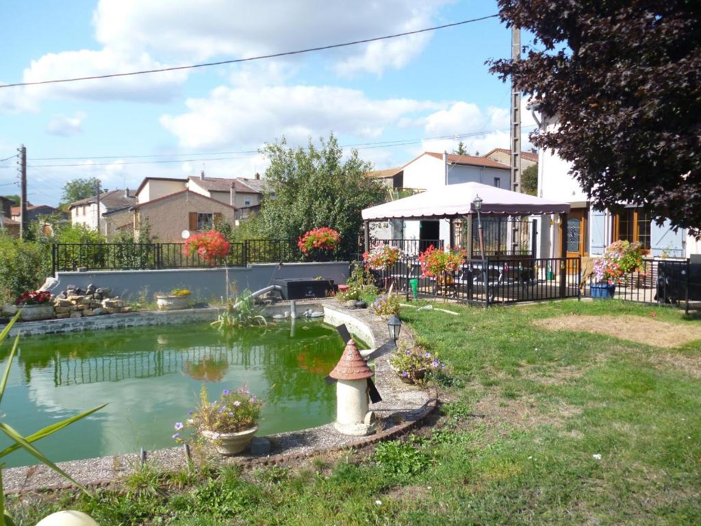 einen Garten mit einem Teich mit einem Haus im Hintergrund in der Unterkunft Guestroom Xivry-Circourt, 1 pièce, 2 personnes - FR-1-584-207 