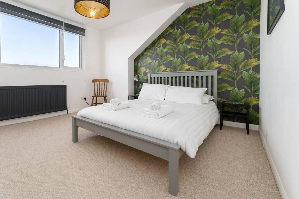 a bedroom with a white bed with a green wall at Light bright & contemporary split-level apartment in Brighton & Hove