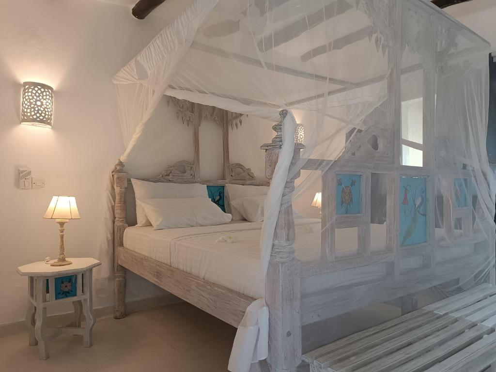 a bedroom with a white bed with a canopy at Pole Pole Beach House in Watamu