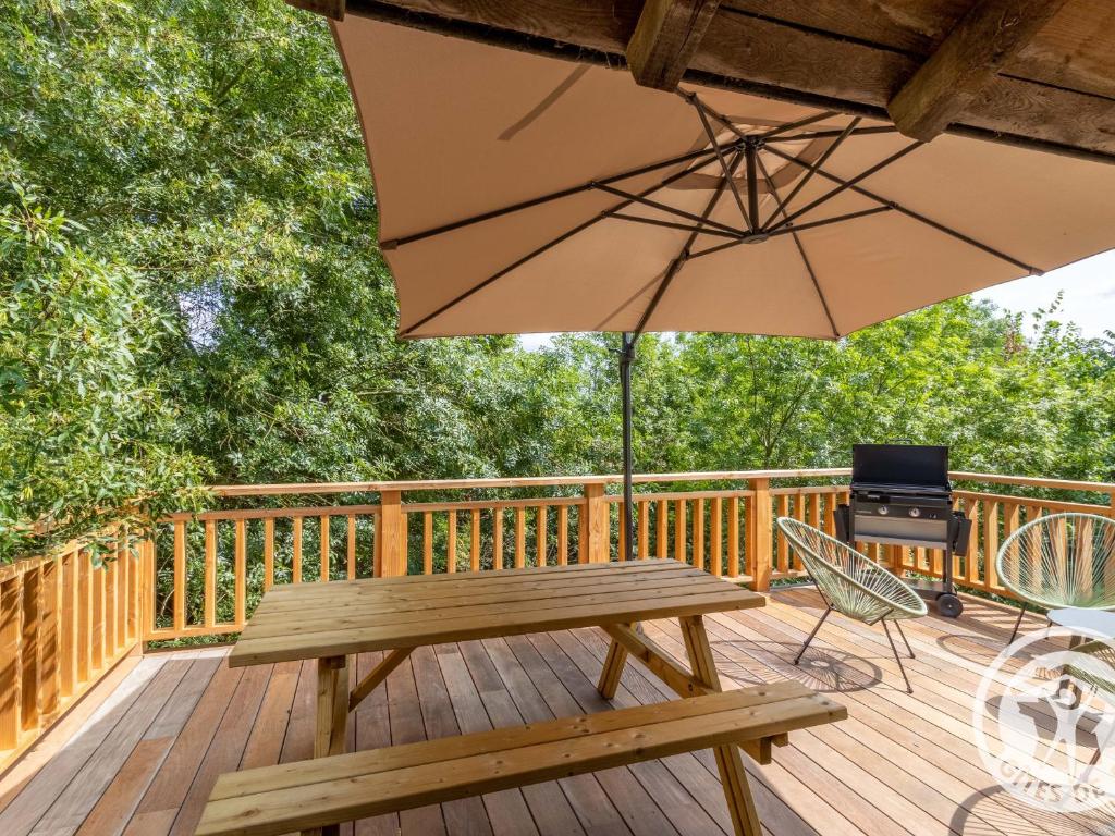 una terrazza in legno con tavolo da picnic e ombrellone di Maison de Vacances Rénovée sur l'Île Fluviale de Chalonnes, Terrasse, BBQ, Prêt de Vélos - FR-1-622-61 a Chalonnes-sur-Loire