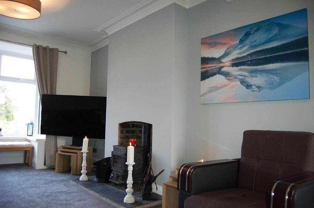 a living room with a tv and a couch and candles at Idris View Family Holiday Home in Tywyn