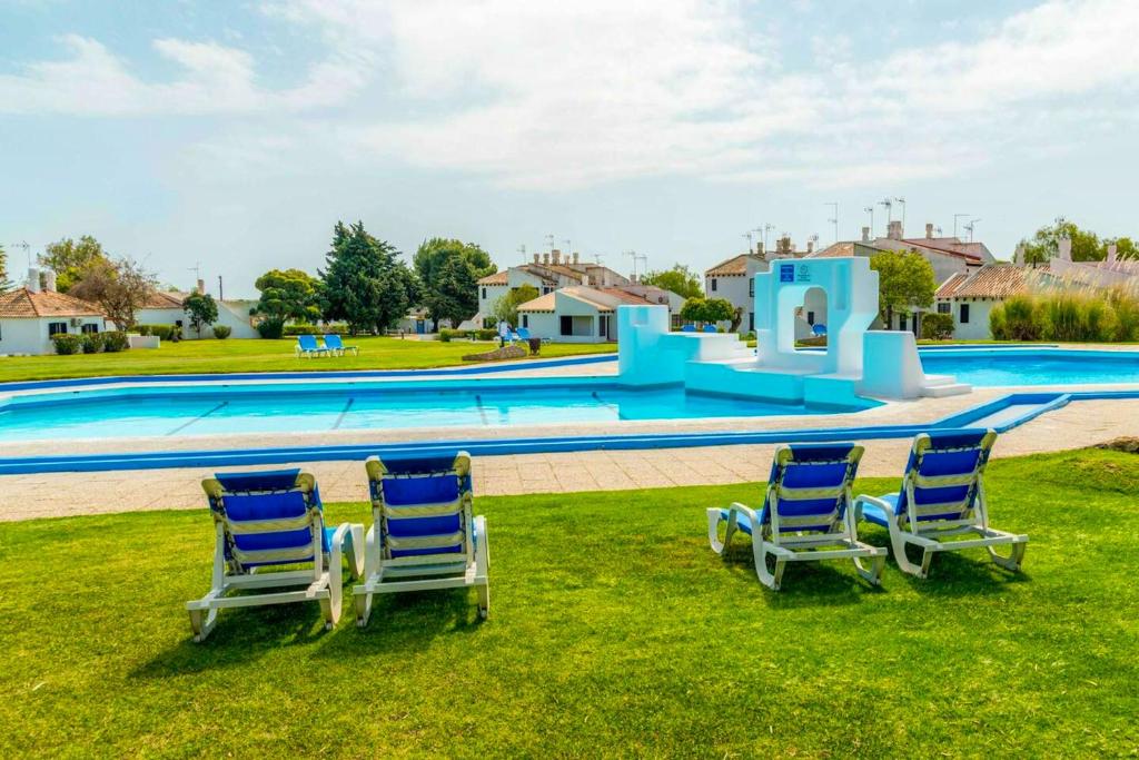 タヴィラにあるOne bedroom property with shared pool and terrace at Таvira 1 km away from the beachのスイミングプールの近くの芝生に座った青い椅子2脚