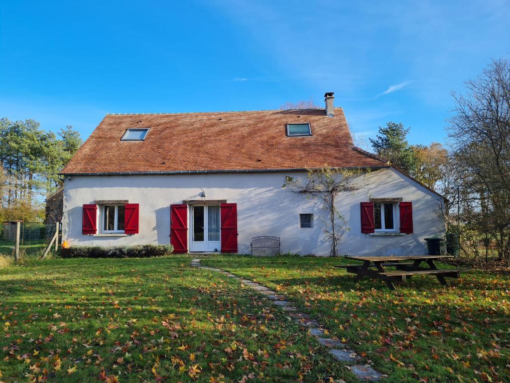 una grande casa bianca con persiane rosse e una panchina di Gîte Donnery, 4 pièces, 6 personnes - FR-1-590-380 a Donnery