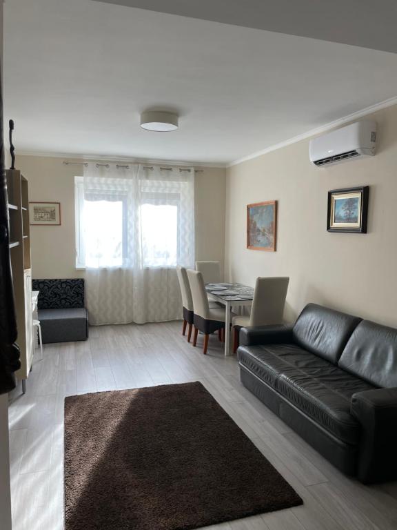salon z czarną skórzaną kanapą i stołem w obiekcie SunCity Apartman w Segedynie