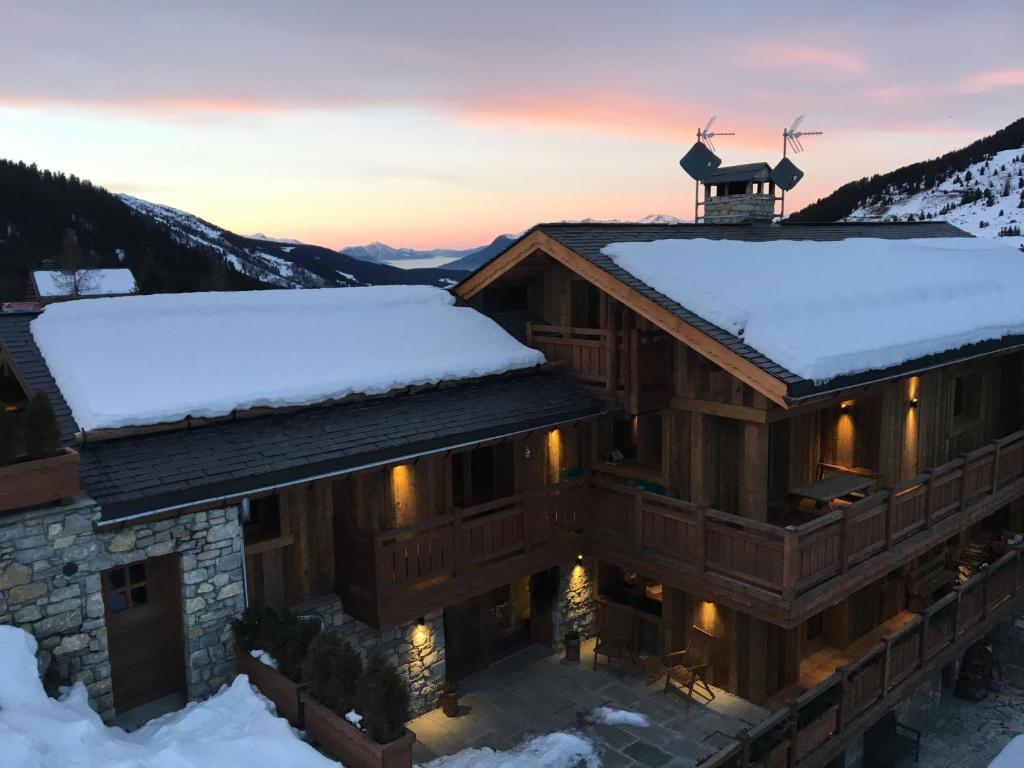 a house with snow on the roof at sunset at Chalet La Grande Ourse Meribel - superior apartment in Les Allues