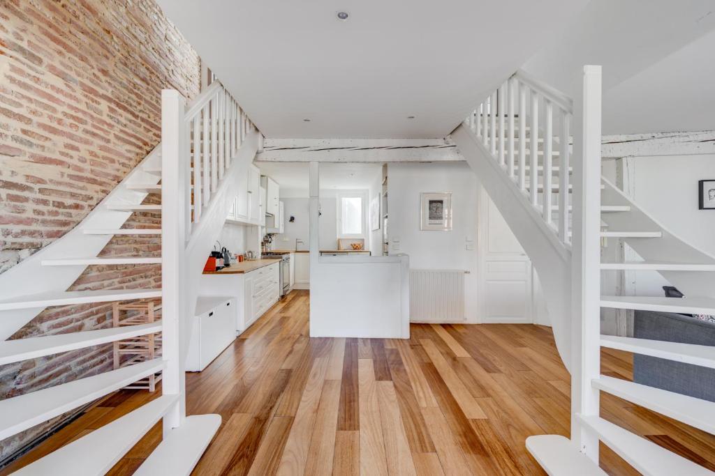 une cuisine avec des escaliers blancs et un mur de briques dans l'établissement Laganne by Yumē, à Toulouse