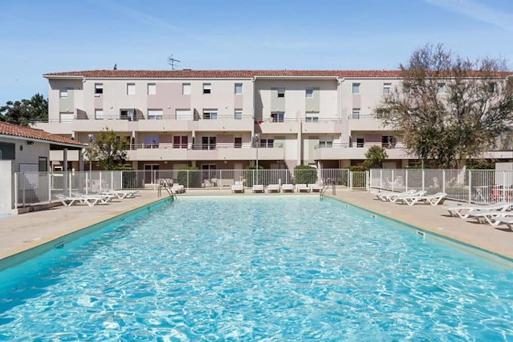 une grande piscine devant un immeuble dans l'établissement Appartement le Grau du roi, au Grau-du-Roi