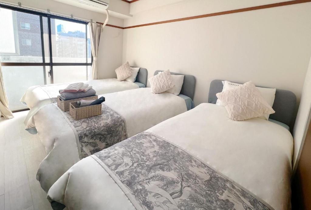 a room with three beds and a window at 江元浅草 in Tokyo