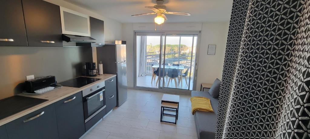 une cuisine avec des placards bleus et un ventilateur de plafond dans l'établissement Les Terrasses du Grand Bleu,6 pers, parking, piscine, au Cap d'Agde