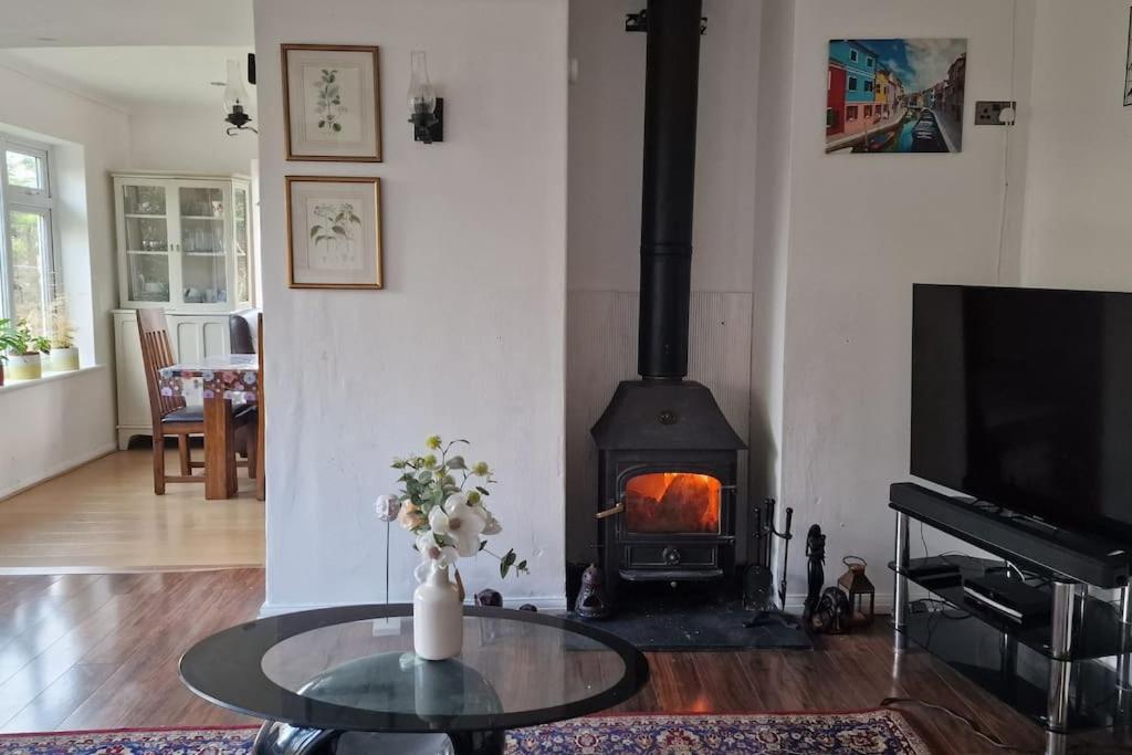 a living room with a fireplace and a table and a stove at Forest view cottage in Nottingham