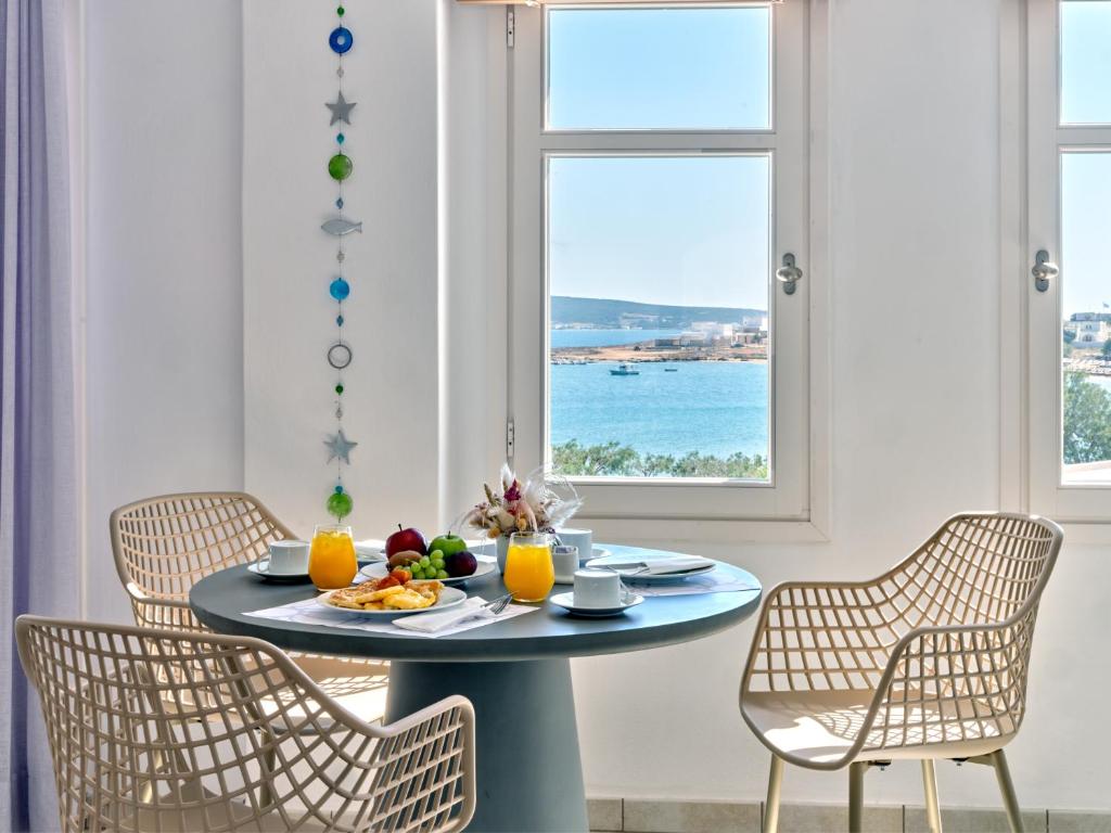 a table with chairs and a plate of food on it at Stelia Mare Boutique Hotel in Naousa