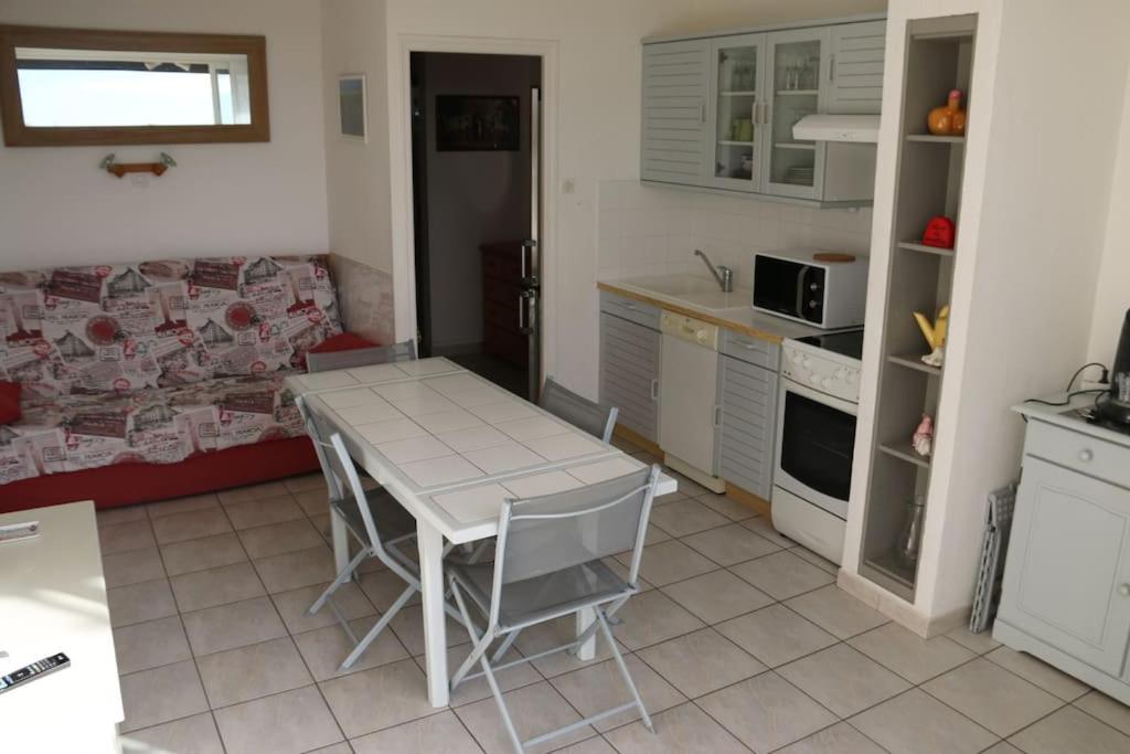 une cuisine avec une table, des chaises et un canapé dans l'établissement Appartement 307, Héliopolis K au village naturiste, au Cap d'Agde