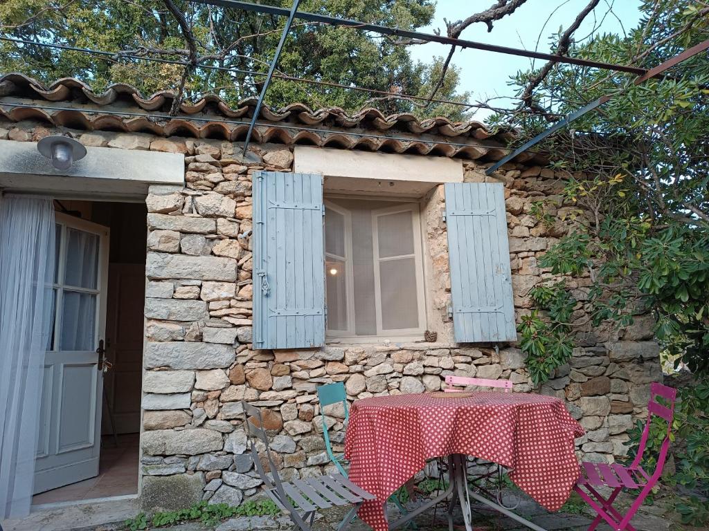 une table devant une maison en pierre avec des fenêtres bleues dans l'établissement Sous la vigne, à Rustrel