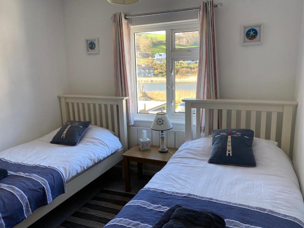 2 camas en una habitación con ventana en Beachside, Torcross, between the Sea and the Ley en Torcross