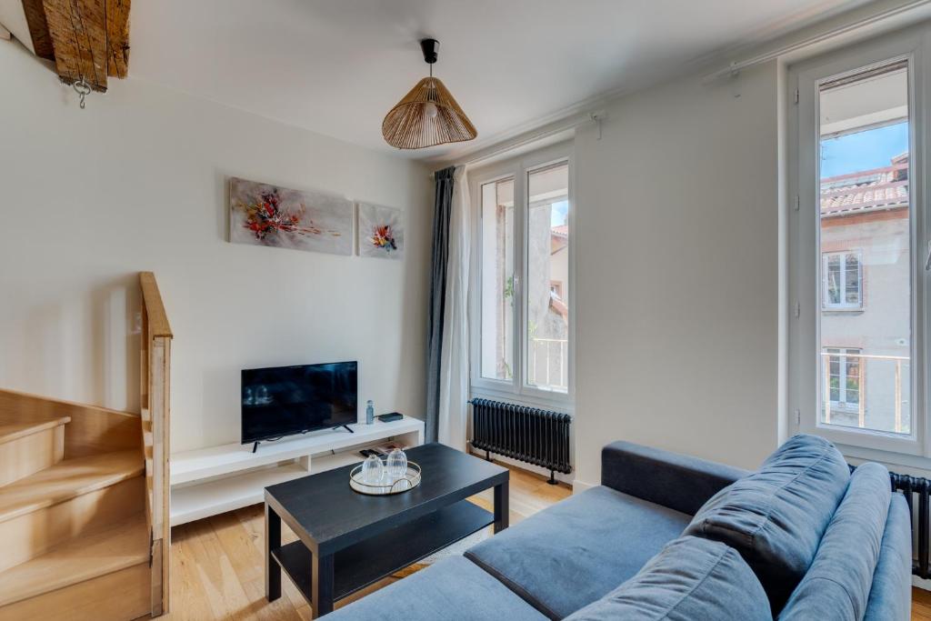 un salon avec un canapé bleu et une télévision dans l'établissement Estrela by Yumē, à Toulouse