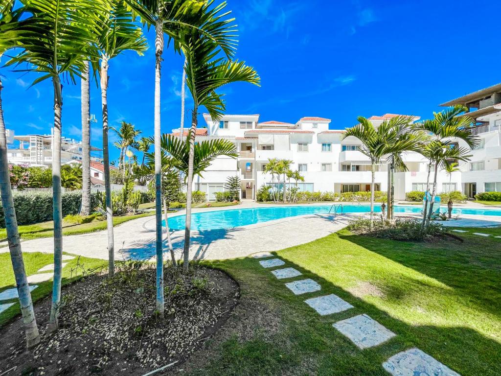 a swimming pool with palm trees in front of a building at Villas & Apartments OCEAN & GARDEN VIEW Vacation HOTEL RENTALS Long Term BAVARO Los Corales in Punta Cana