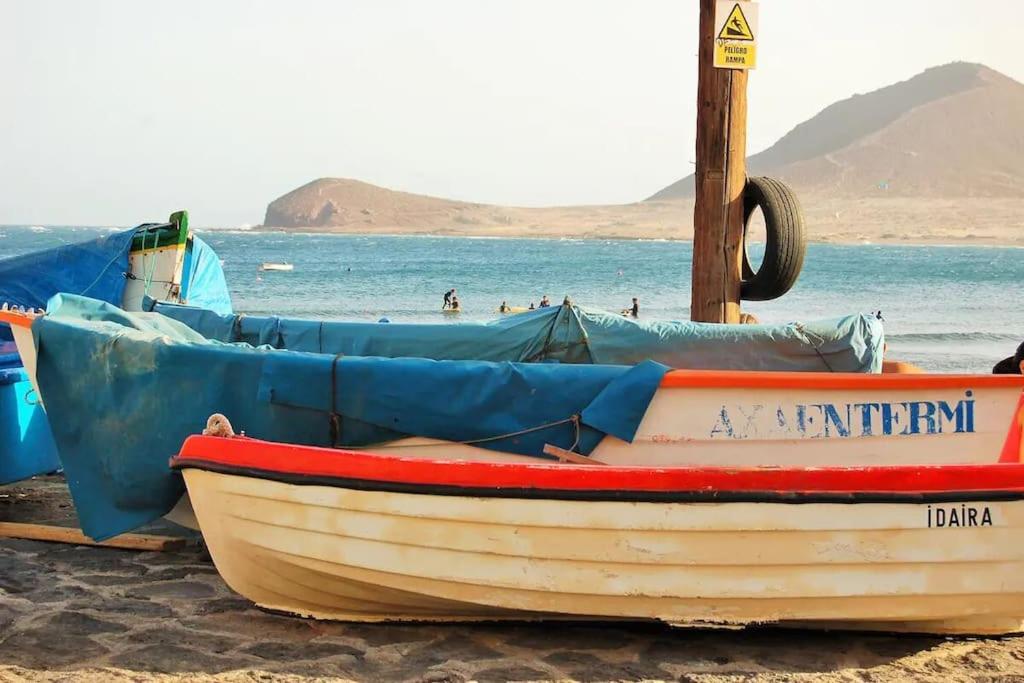 un pequeño barco sentado en una playa junto al agua en Las Carmenes 2, en El Médano