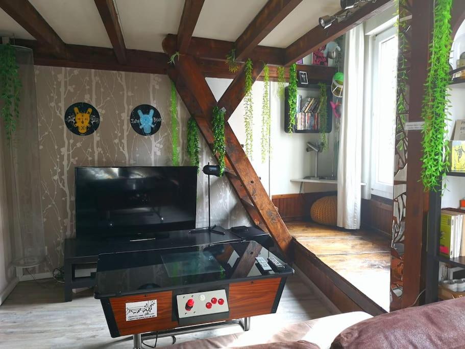 un salon avec une télévision et une table dans l'établissement Atelier d’artiste proche Paris Gare nord/Stade de FR/CDG, à Stains