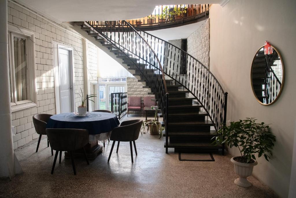 a dining room with a table and a spiral staircase at Anna's Guest House in Gori