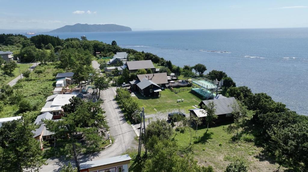 una vista aérea de una casa en una colina cerca del océano en ゲストハウス風の丘 en Tōbetsu