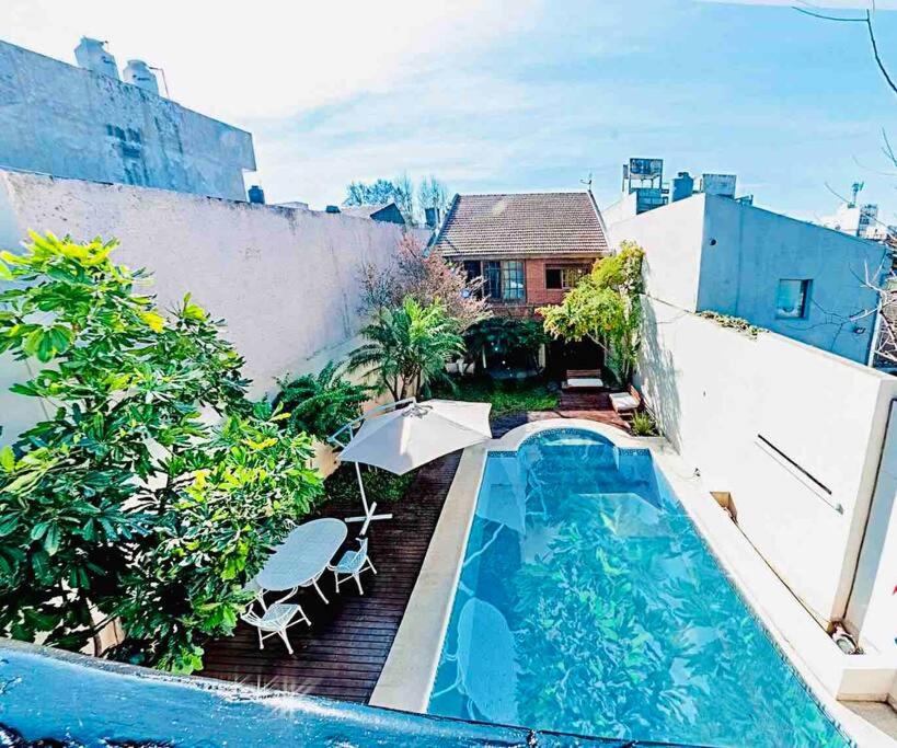 a swimming pool with an umbrella next to a house at Casona en Buenos Aires in Buenos Aires