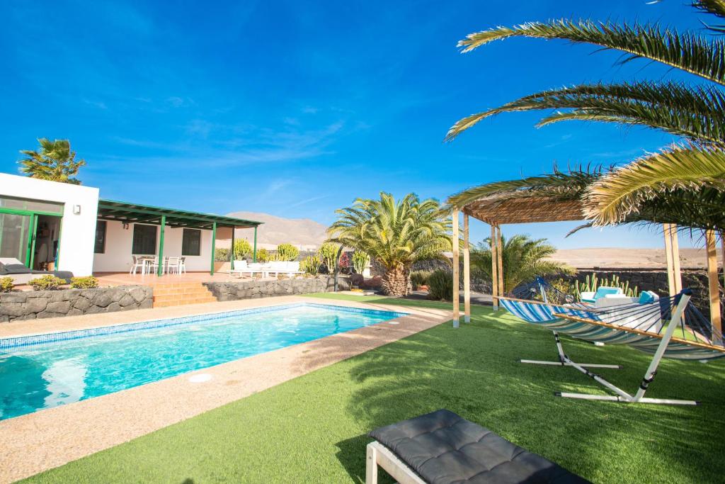 a villa with a swimming pool and palm trees at Villa Papagayo Lanzarote in Playa Blanca