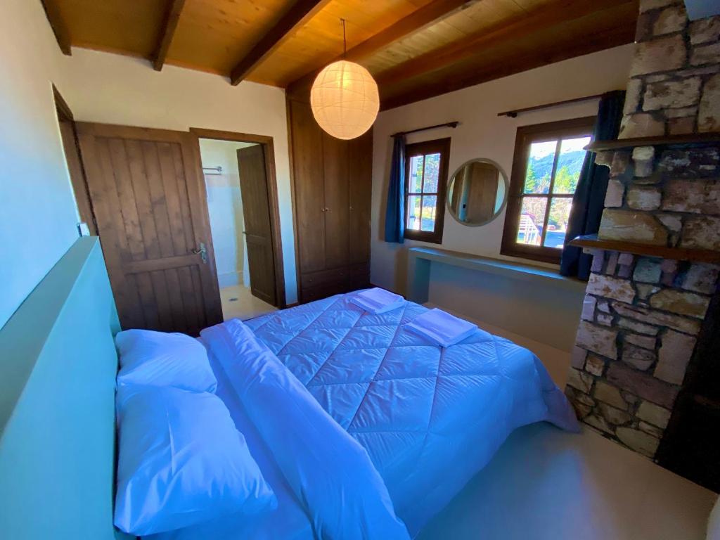 a bedroom with a blue bed and a stone wall at Σκίουρος in Neráïda