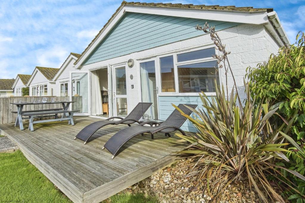 a deck with chairs and a bench on a house at Jamestown 2 in Yarmouth