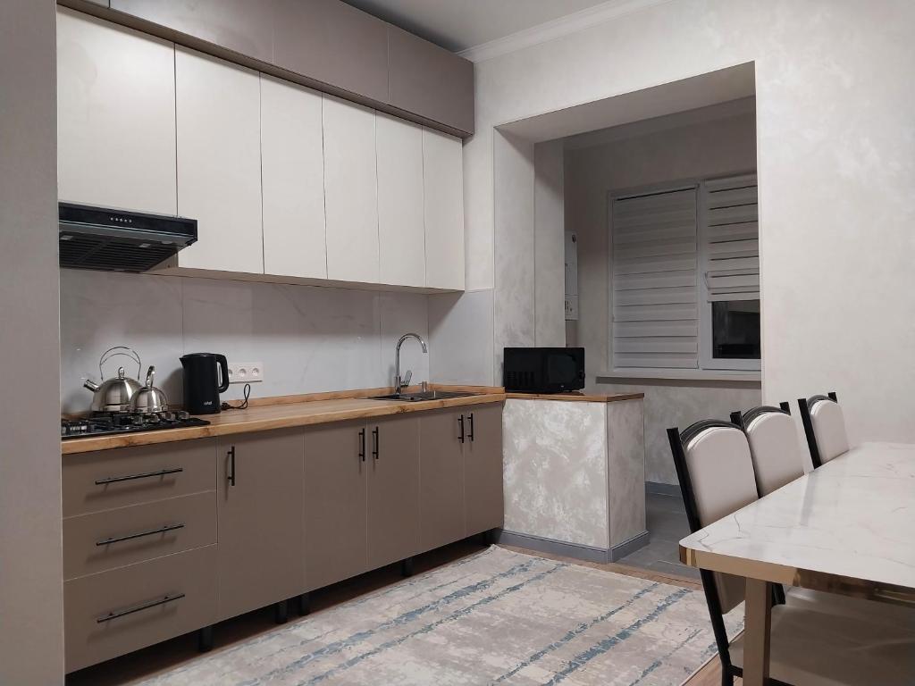 a kitchen with white cabinets and a table with chairs at Квартира in Shymkent
