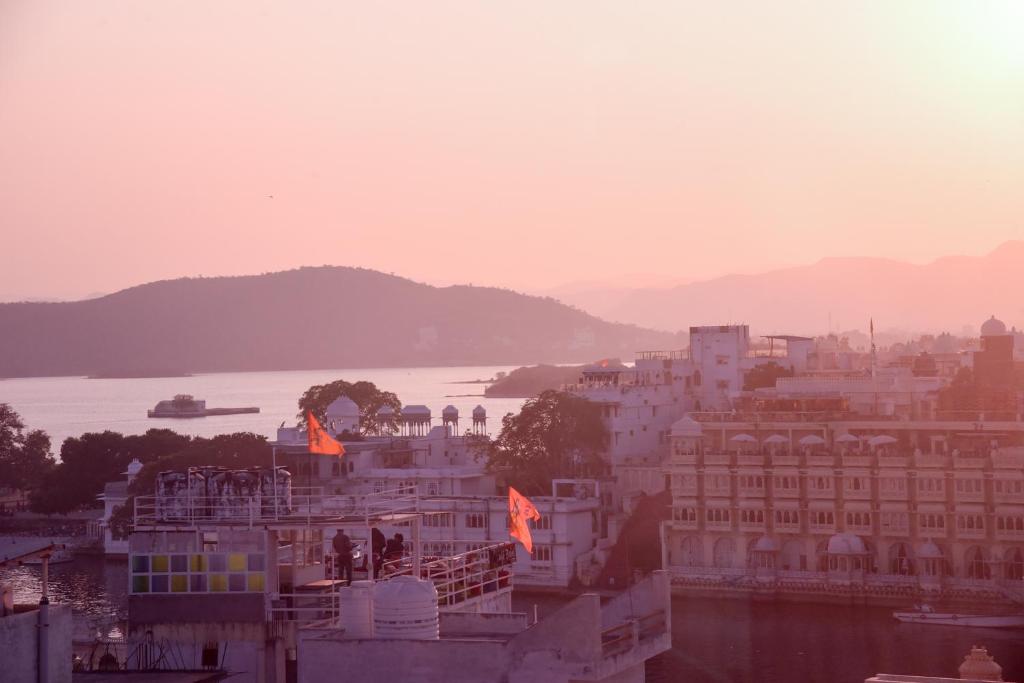 a view of a river and buildings with flags at Sajjan Villa in Udaipur
