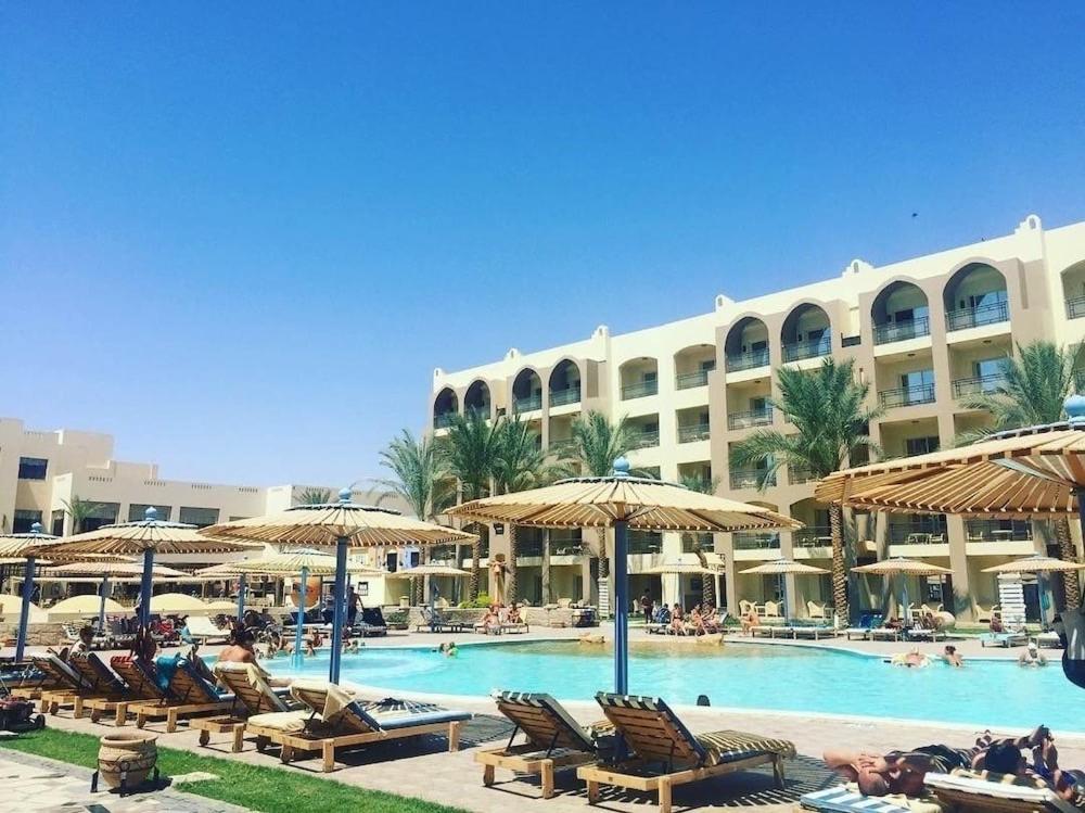 a resort with a swimming pool with chairs and umbrellas at Private 3 bdrm apartment at ElKarma Aqua Beach Reaort in Hurghada