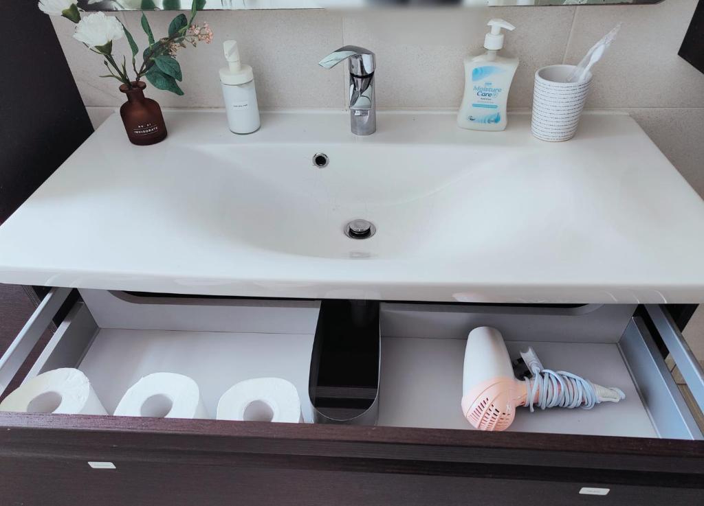 a bathroom sink with cleaning products in a drawer at TAAY -Luxurious 3 bedroom house in South Norwood