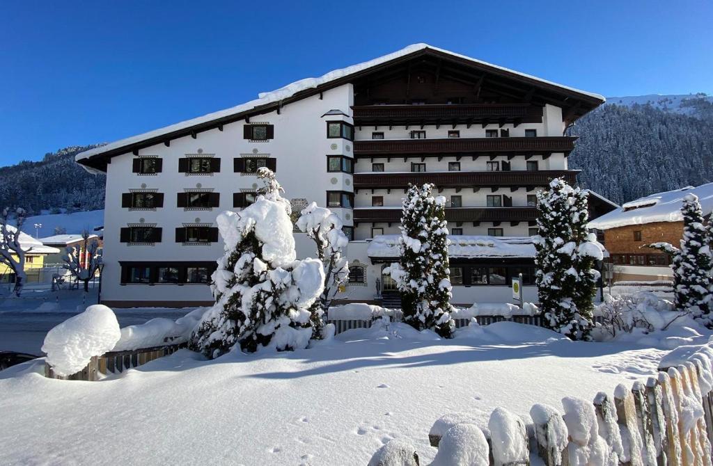 聖安東阿爾貝格的住宿－阿爾山酒店，一座大建筑前面有雪覆盖的树木