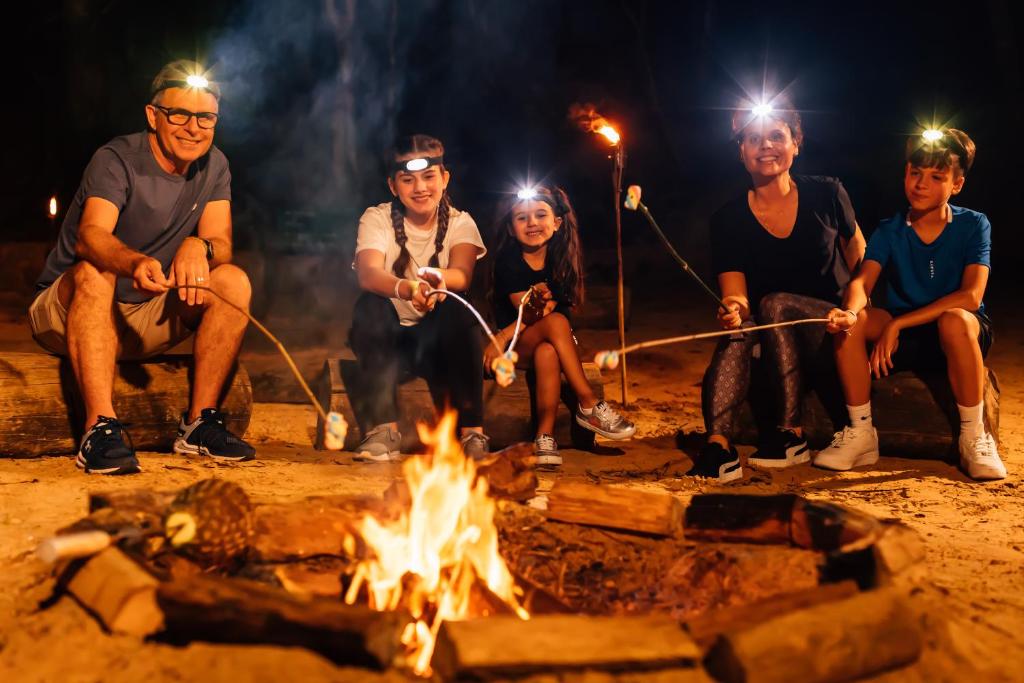 a group of people sitting around a fire at Costao do Santinho Resort All Inclusive in Florianópolis