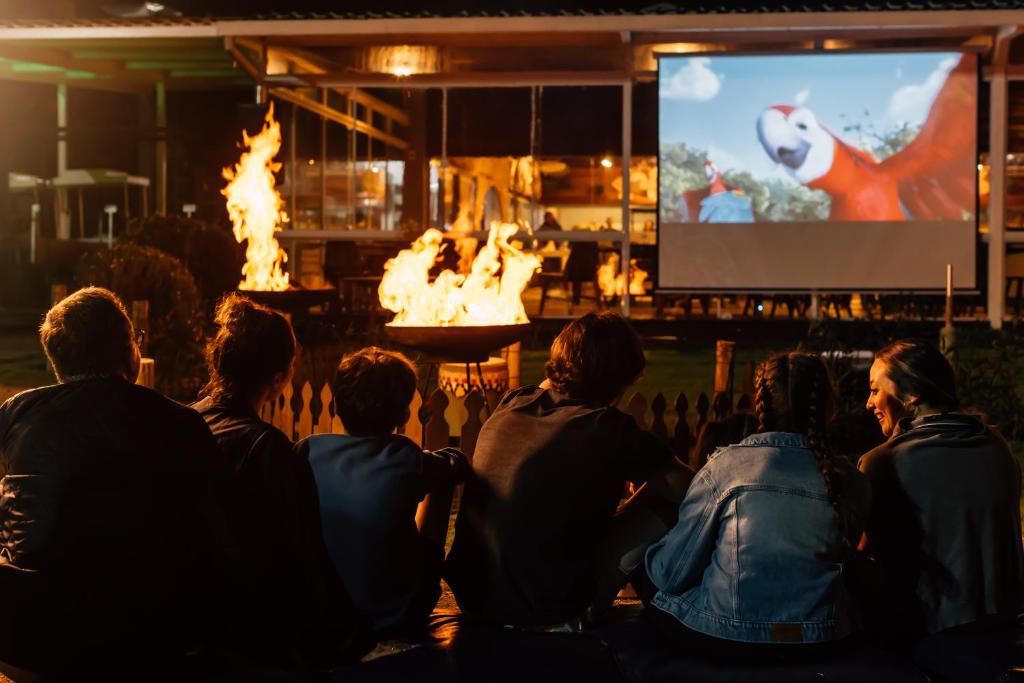 a group of people sitting around a fire pit watching a movie at Costao do Santinho Resort All Inclusive in Florianópolis