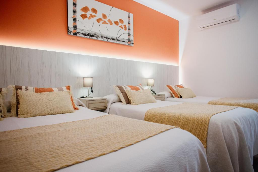 three beds in a hotel room with an orange wall at Apartamentos Turisticos Mastil 16 P2 in Málaga