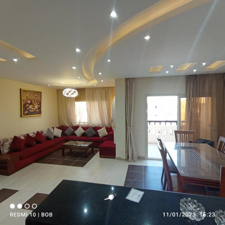 a living room with a red couch and a table at Private 3 bdrm apartment at ElKarma Aqua Beach Reaort in Hurghada