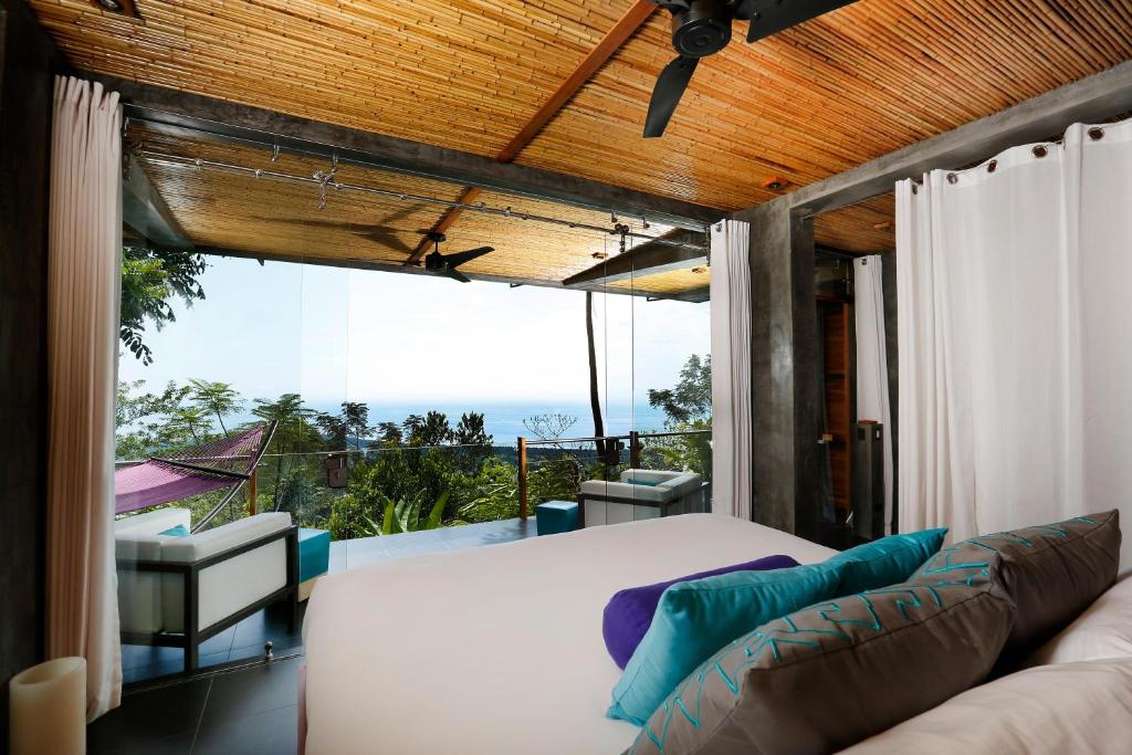 a room with a bed and a couch on a balcony at Kura Boutique Hotel Member of the Cayuga Collection in Uvita