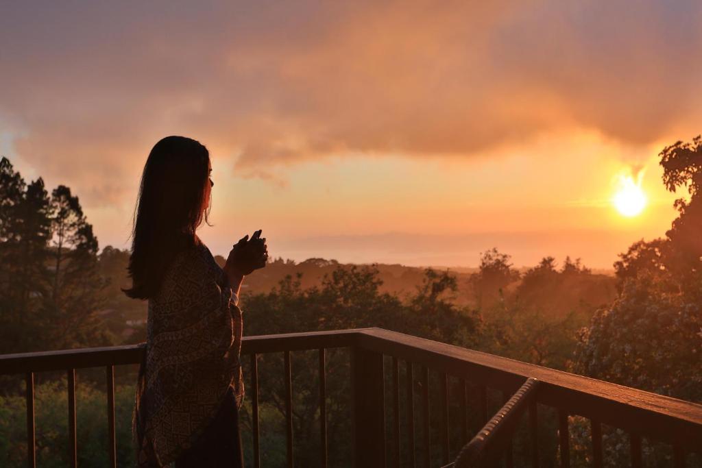 a woman standing on a balcony watching the sunset at Senda Monteverde Hotel Member of the Cayuga Collection in Monteverde Costa Rica