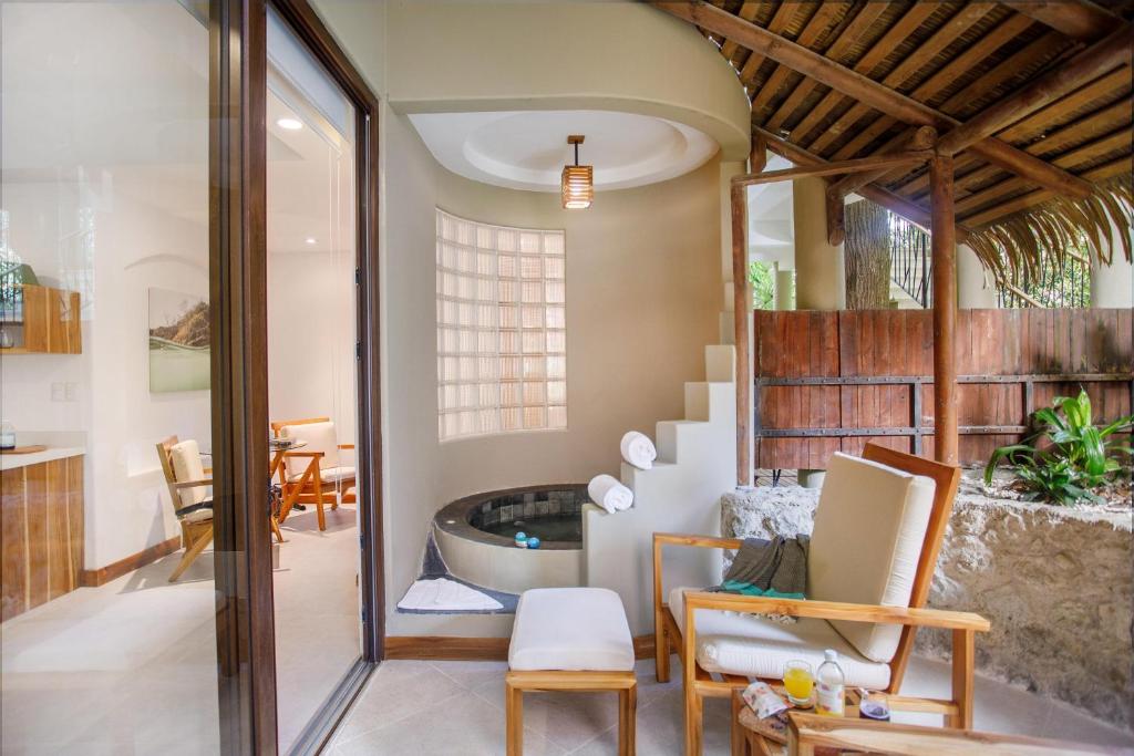 a living room with a tub and a table and chairs at Arenas Del Mar Beachfront & Rainforest Resort Member of the Cayuga Collection in Manuel Antonio