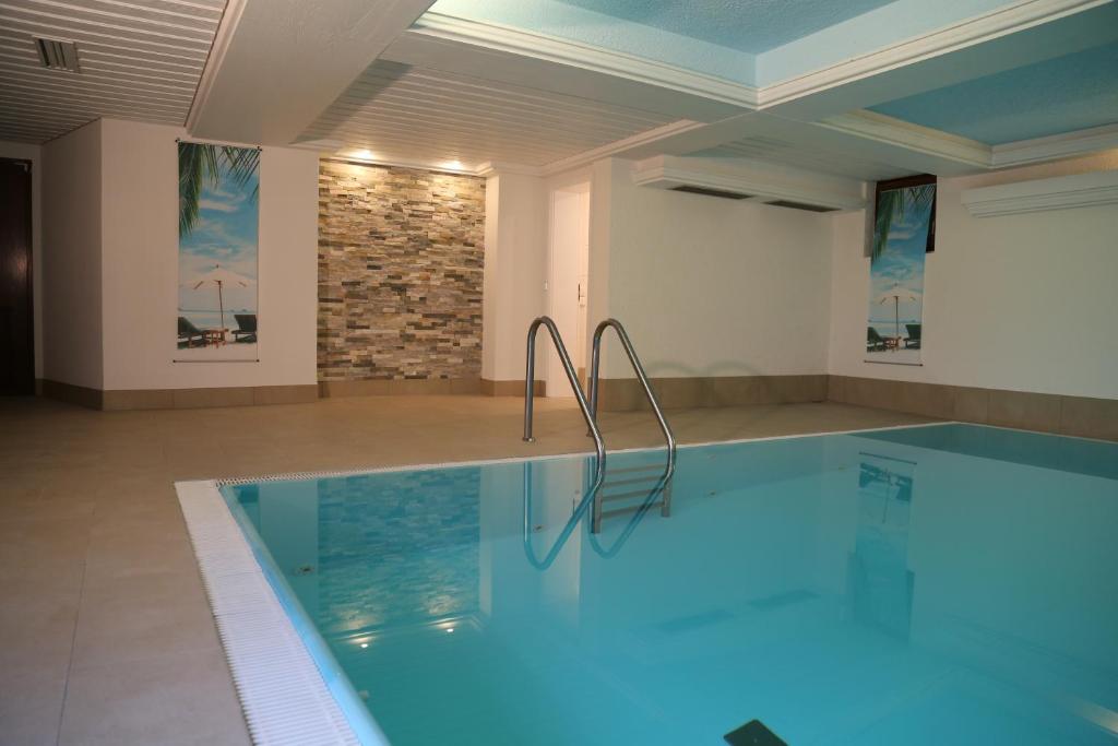 uma piscina num quarto com uma parede de pedra em Goldener Hahn Baiersbronn - Ferienwohnungen mit Hotel Service em Baiersbronn