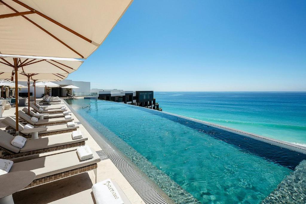 una piscina con tumbonas y el océano en Residential Retreat 2 Bedroom Suite Garza Blanca Los Cabos Resort & Spa en Cabo San Lucas