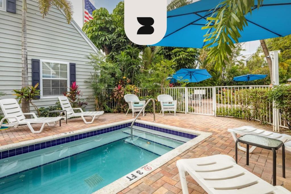 a swimming pool in front of a house with chairs and umbrellas at Road's End by Brightwild in Key West