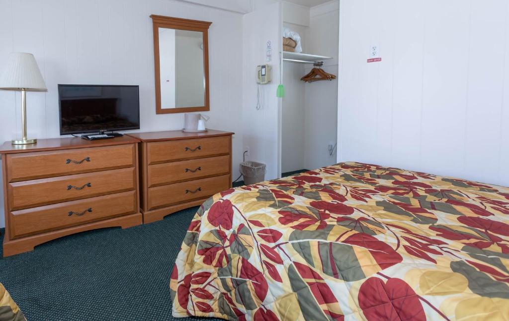 una camera con un letto e un comò con una televisione di Fish Tales Boardwalk Inn & Ocean Mecca Motel a Ocean City