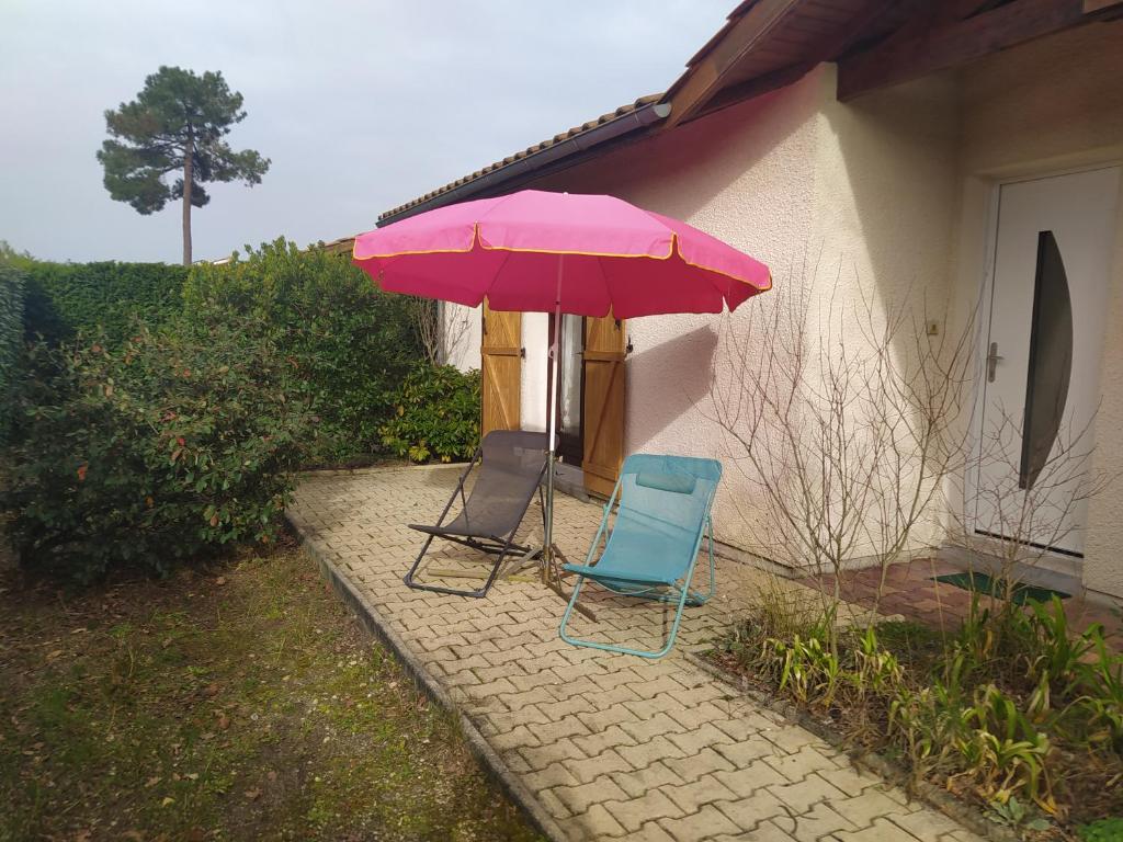 2 chaises et un parasol rose à côté d'une maison dans l'établissement Villa Nancea Bassin Arcachon Gujan Mestras, à Gujan-Mestras