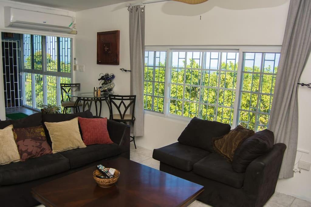 a living room with two couches and a table at The Biltons - 6 min from airport- A/C in all rooms in Montego Bay