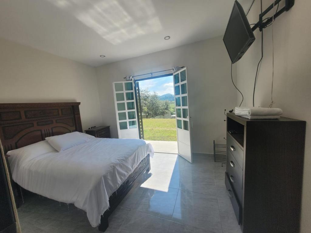 a bedroom with a bed and a flat screen tv at Cabaña Na-tatik in Ocosingo