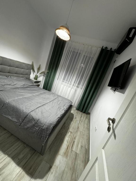 a bedroom with a bed and a window with green curtains at Apartament MaGiFa Mamaia Nord in Năvodari